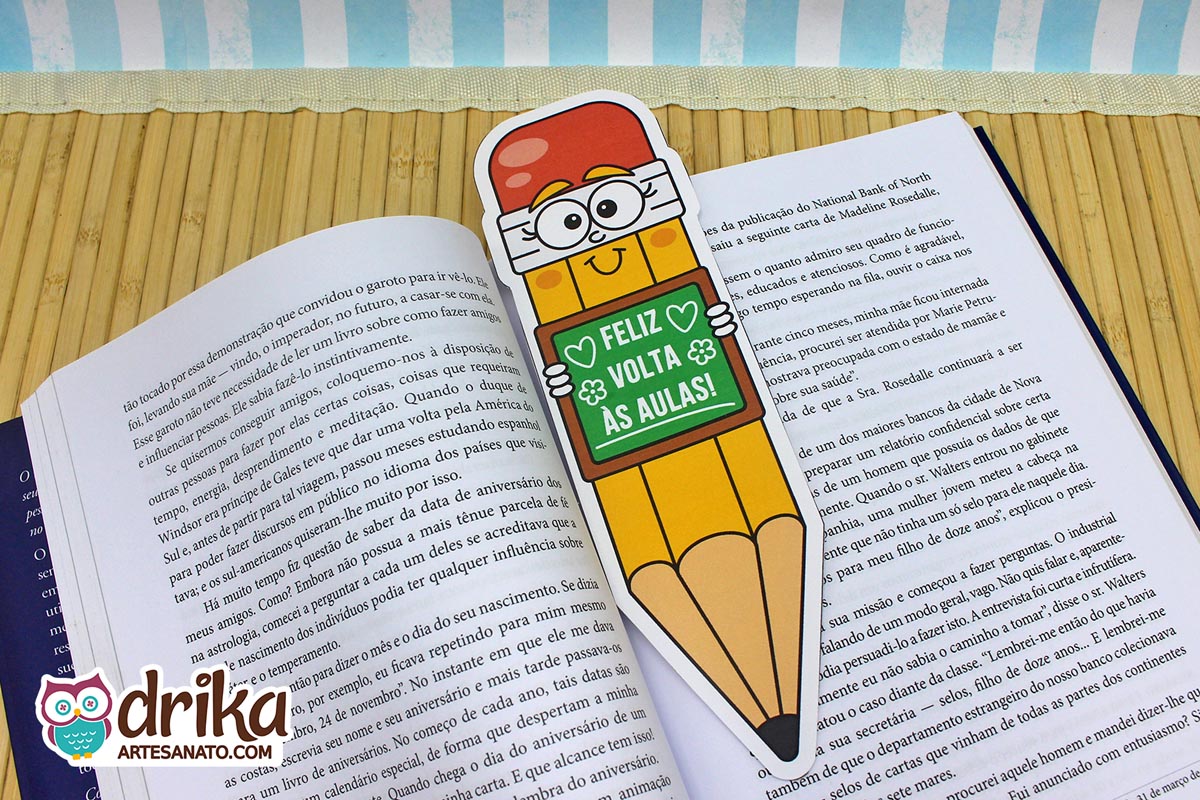 Marcador de página em formato de lápis gigante com carinha fofa e mensagem "Feliz Volta às Aulas" em livro aberto
