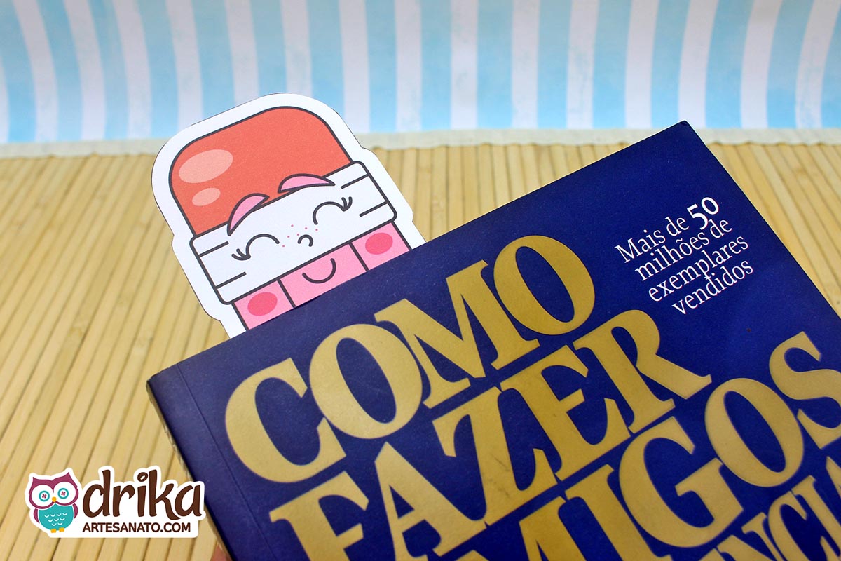 Marcador de página de borracha rosa com carinha sorridente saindo de um livro azul escuro