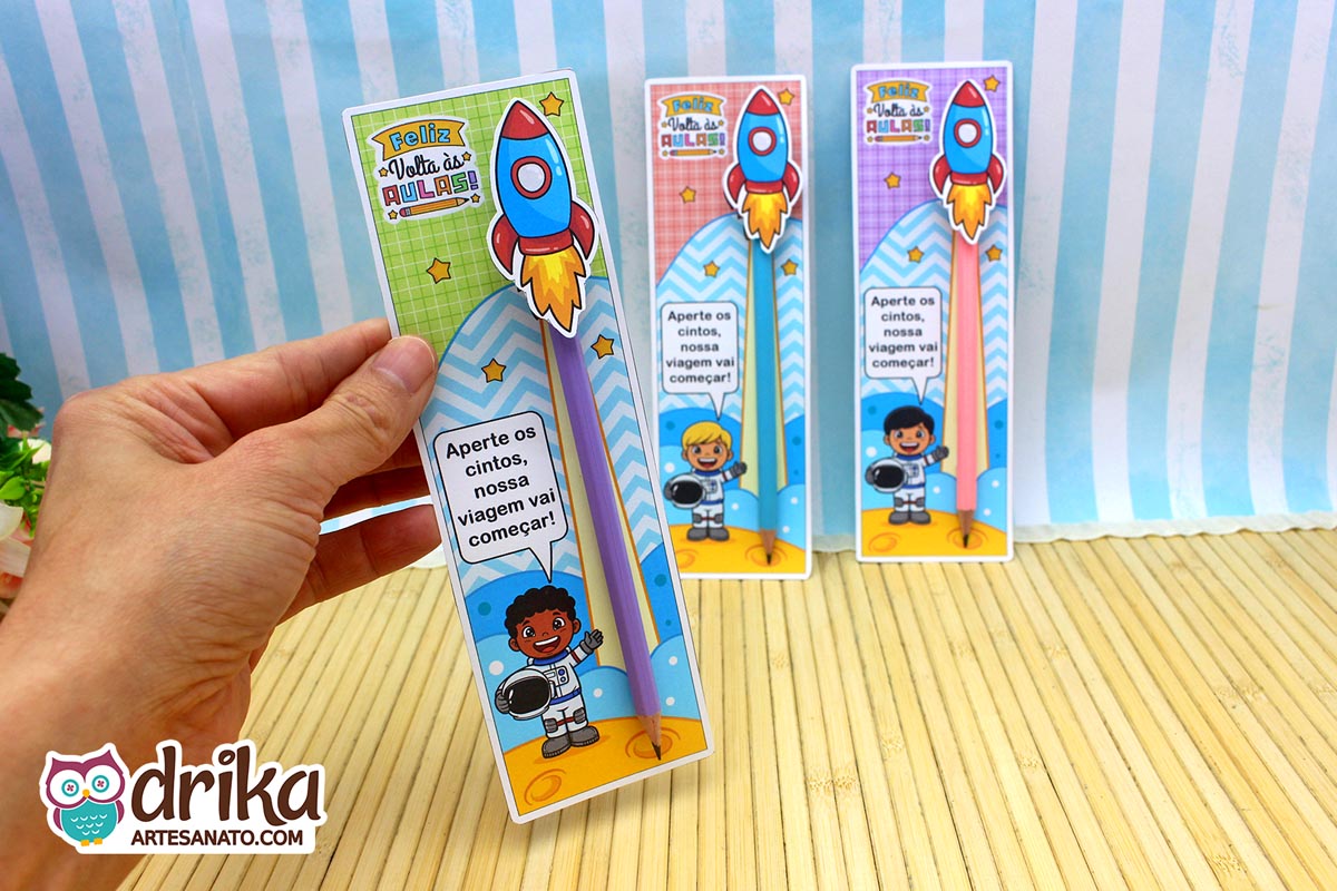 Mão segurando cartão porta-lápis de astronauta menino de cabelo crespo, com lápis roxo e foguete 3D