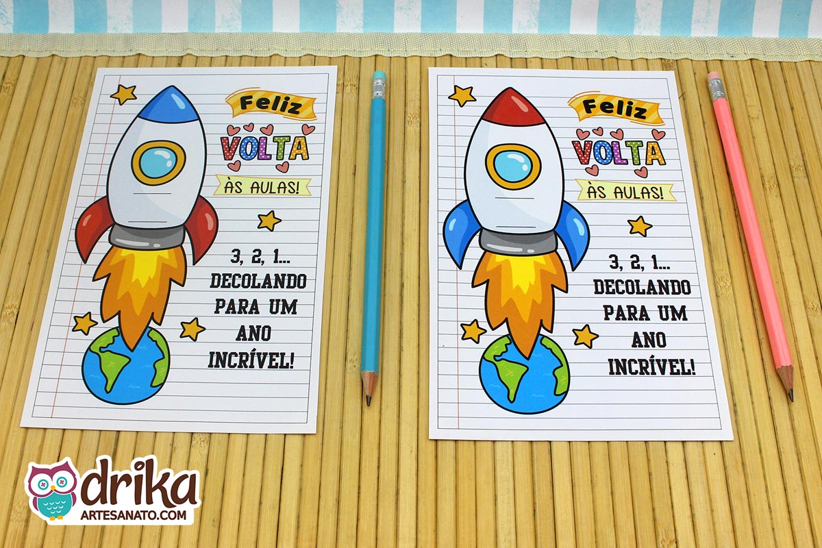 Dois cartões porta-lápis de papel com foguetes coloridos, mensagens de "Feliz Volta às Aulas" e lápis azul e rosa ao lado
