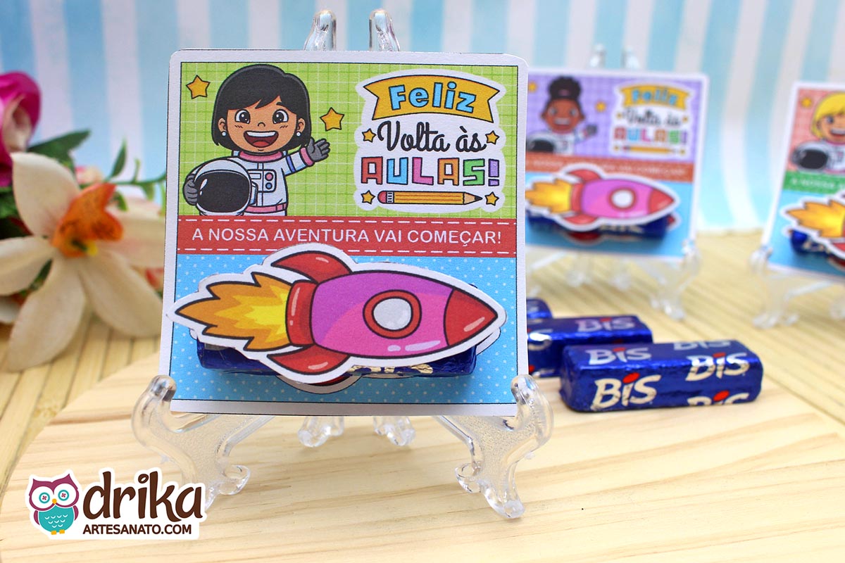 Cartão porta-bis com menina astronauta de cabelo preto, bis de chocolate e foguete 3D rosa afixado, em cavalete