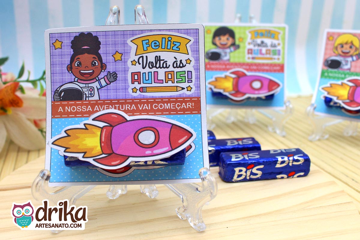 Cartão porta-bis com menina astronauta de cabelo crespo, bis de chocolate e foguete 3D rosa afixado, em cavalete