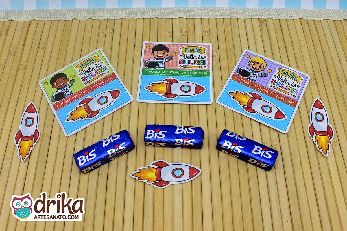 Três cartões porta-bis de astronautas meninos com bis encaixados e foguetes extras soltos sobre superfície de bambu