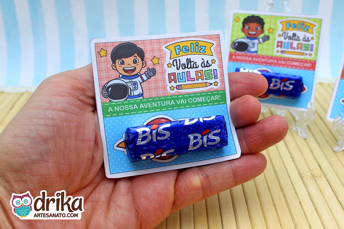 Mão segurando cartão porta-bis de astronauta menino com cabelo preto liso e bis azul encaixado, sem foguete extra