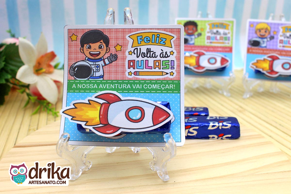 Cartão porta-bis de astronauta menino com cabelo preto liso, bis azul e foguete 3D colado, em suporte transparente