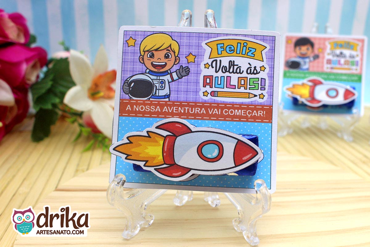 Cartão porta-bis de astronauta menino com cabelo loiro, bis azul e foguete 3D colado, em suporte transparente