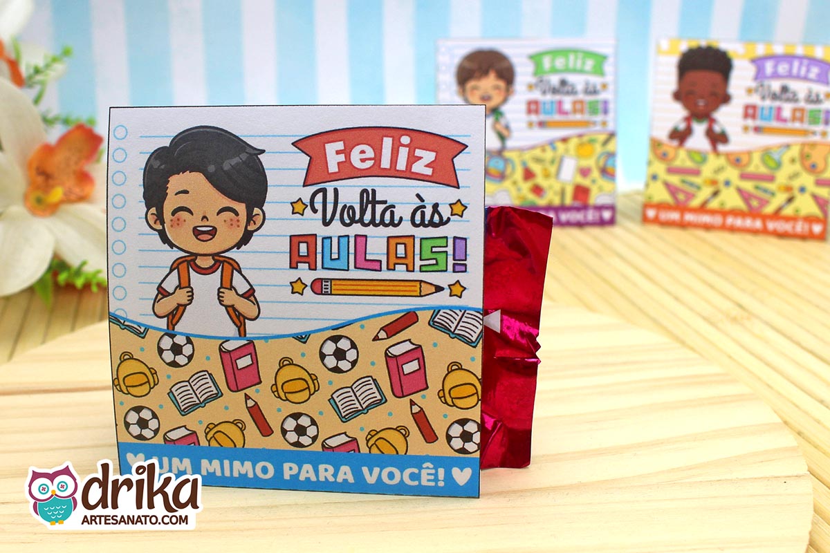 Porta-bombom de papel com menino de cabelo preto liso e mochila, em fundo de caderno. Decorado com bolas de futebol e livros