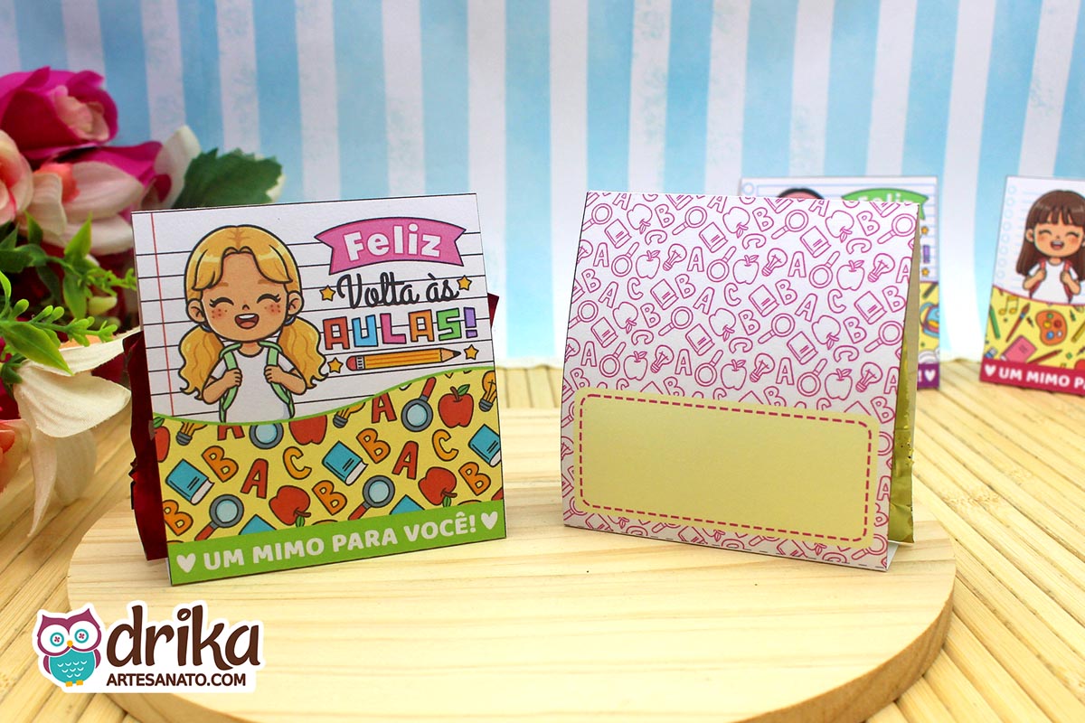 Dois porta-bombons de papel em base de madeira, um com frente de menina loira e outro mostrando o verso para mensagem