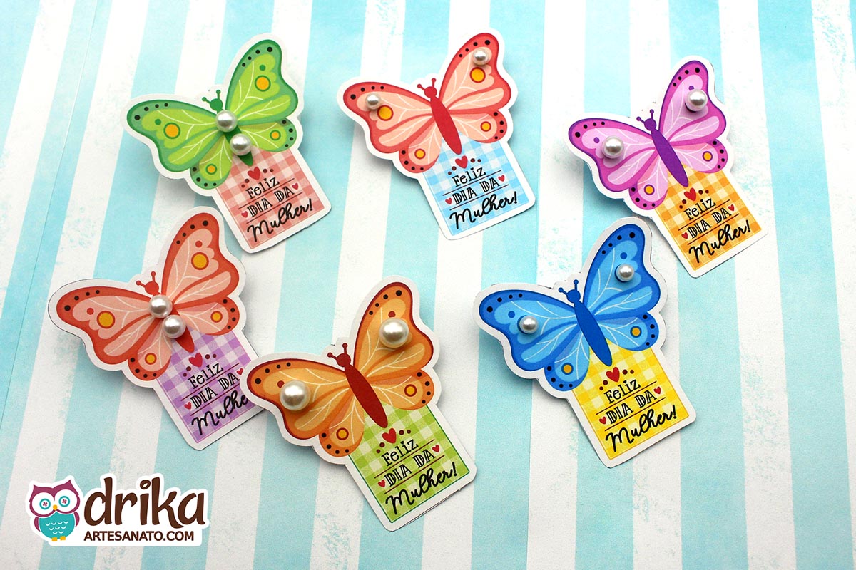 Seis cartões porta-pérola de borboleta coloridos com pérolas brancas, cada um com a mensagem "Feliz Dia da Mulher"