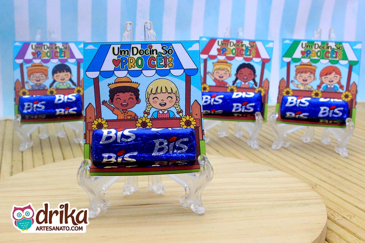 Quatro lembrancinhas Porta-bis Caipiras Cute montadas com chocolates Bis, exibidas em suportes transparentes. O modelo em primeiro plano mostra um menino negro e uma menina loira.