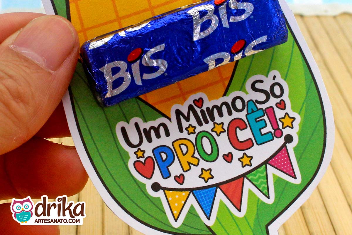 Close-up do porta-bis de milho com frase "Um Mimo Só Pro Cê!" e bandeirinhas, com Bis azul encaixado acima