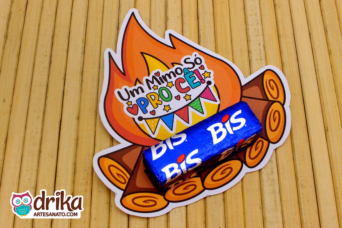 Porta-bis de papel com desenho de fogueira e a frase Um Mimo Só Pro Cê com um chocolate Bis azul sobreposto