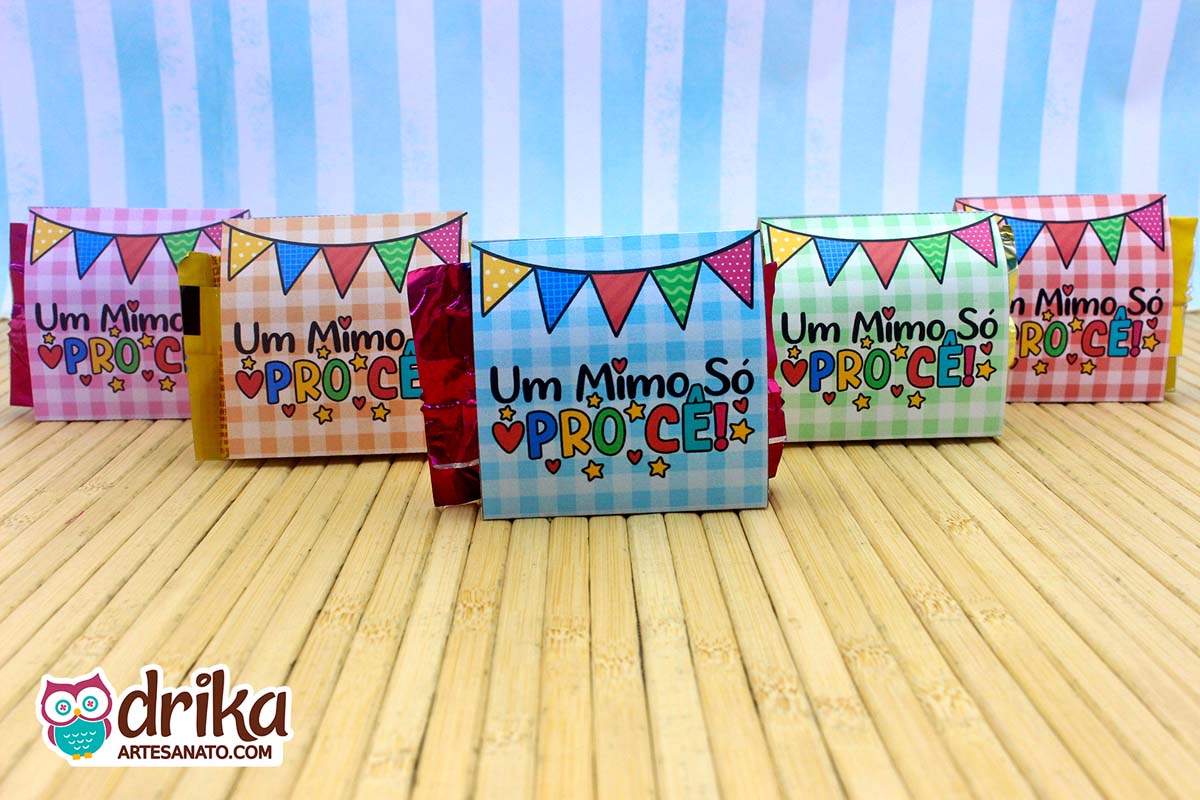 Cinco porta-bombons de papel exibindo o verso com fundo xadrez, bandeirinhas juninas e a frase "Um Mimo Só Pro Cê!"
