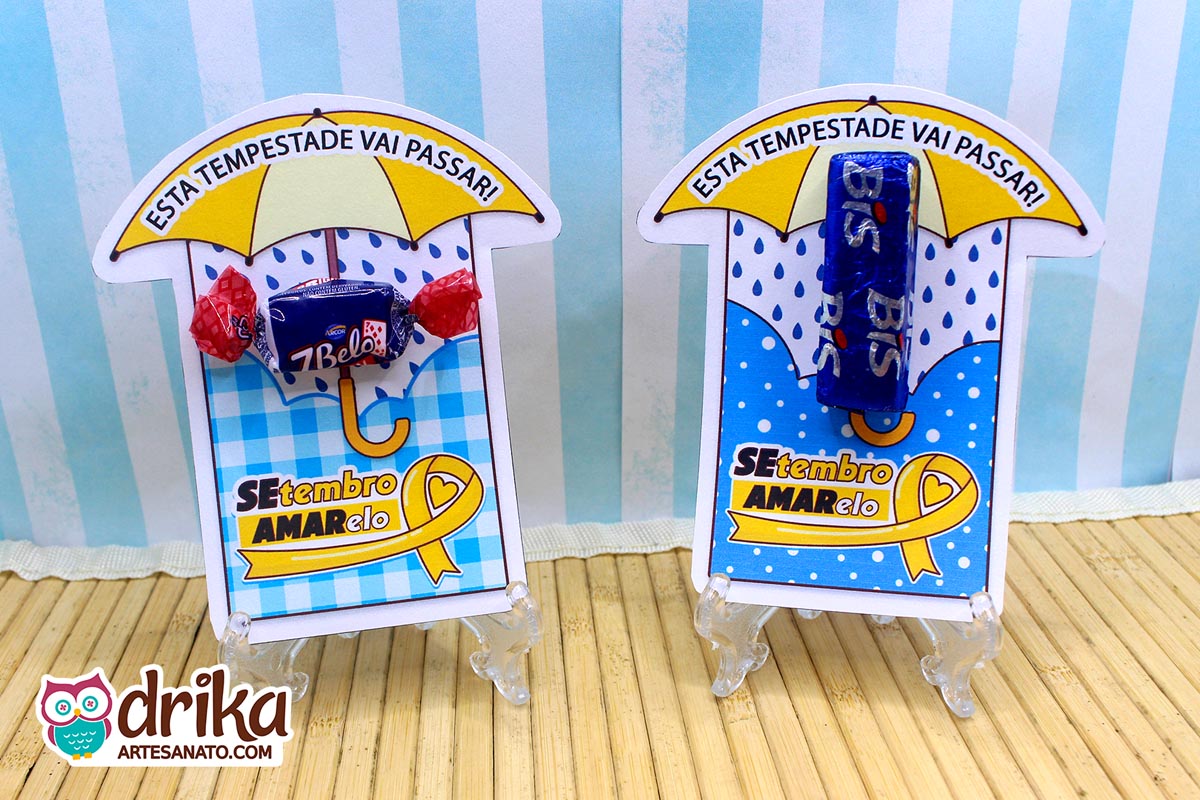 Dois porta-bis de papel com estampa de guarda-chuva e laço amarelo, um com bala 7Belo e outro com chocolate Bis