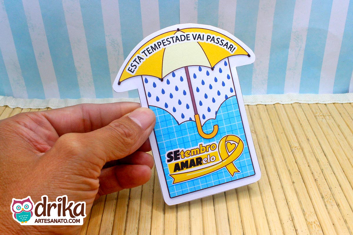 Mão segurando cartão de papel em formato de guarda-chuva com estampa de padrão quadriculado azul